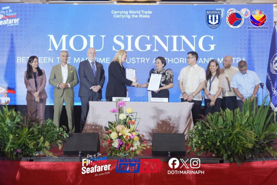 A group of people stand on stage during an MOU signing ceremony between the Maritime Industry Authority and MSIPA, with documents exchanged and a backdrop displaying event details.