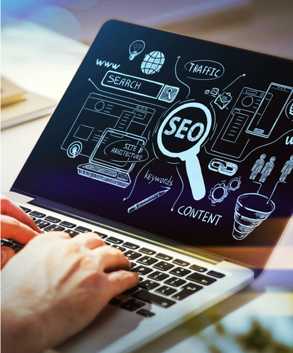 Person typing on a laptop displaying an SEO schematic with terms like search, traffic, keywords, and content, illustrated in chalkboard style.
